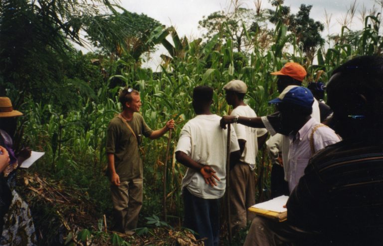 Photograph of men standing in jungle surroundings