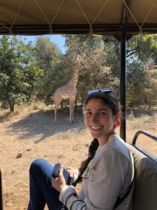 Herrero poses with a giraffe while conducting field research in Africa