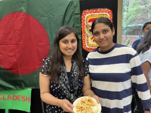 two students pose with food at culture night